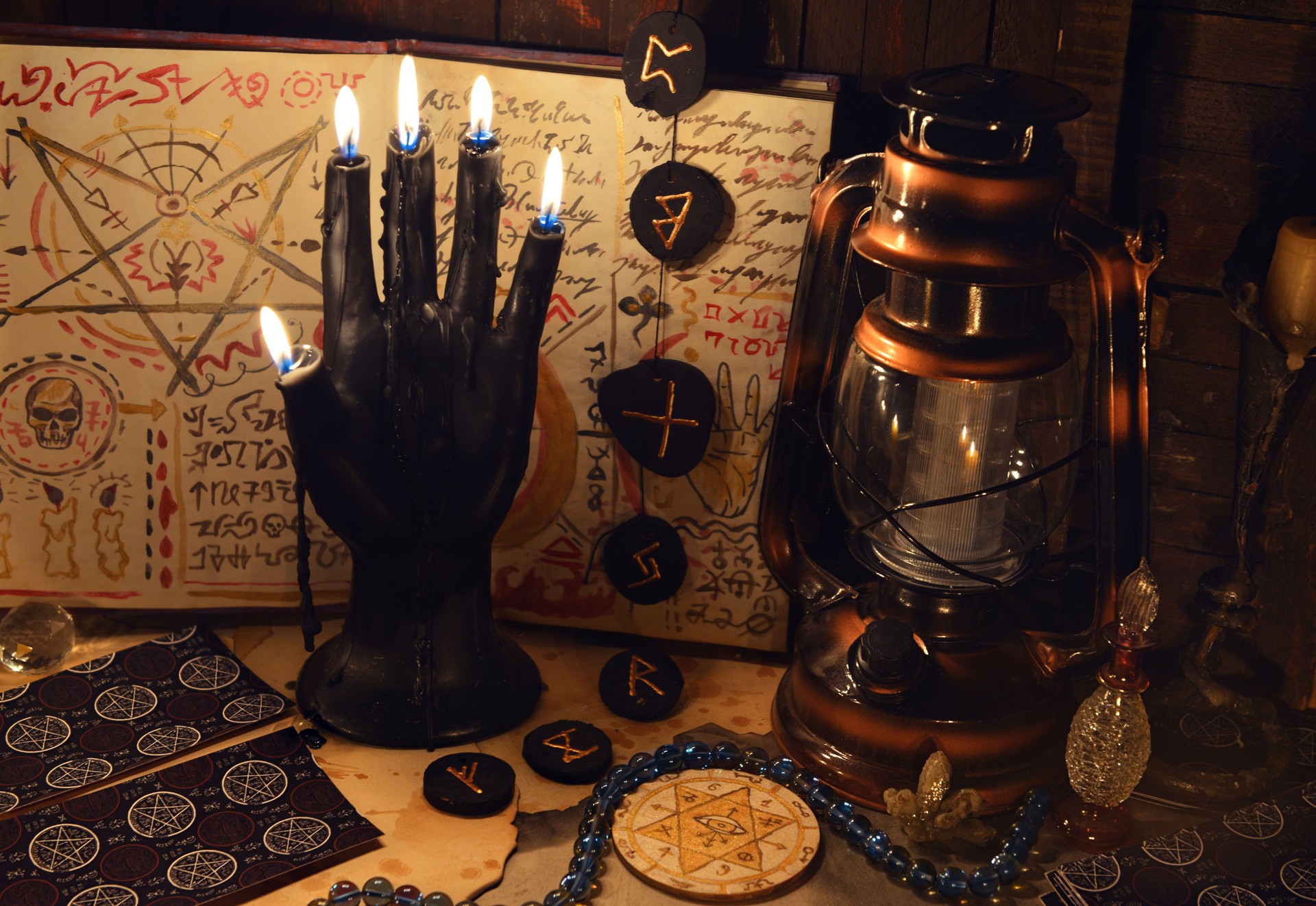 Mystic still life with tarot cards, runes and black candle as scary hand on witch table. Occult, esoteric, wicca, Halloween and gothic concept. No foreign language, all symbols are fictional. Mystic still life with tarot cards, runes and black candle as scary hand on witch table. Occult, esoteric, wicca, Halloween and gothic concept. No foreign language, all symbols are fictional.