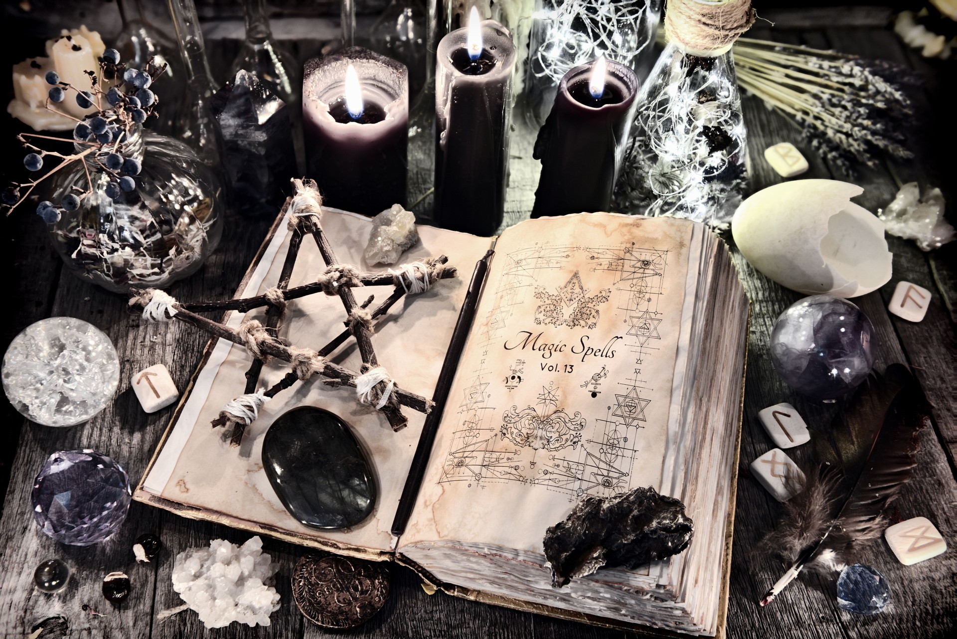 Open witch book with pentagram, black candles, stones, crystals and magic ritual objects Open witch book with pentagram, black candles, stones, crystals and magic ritual objects