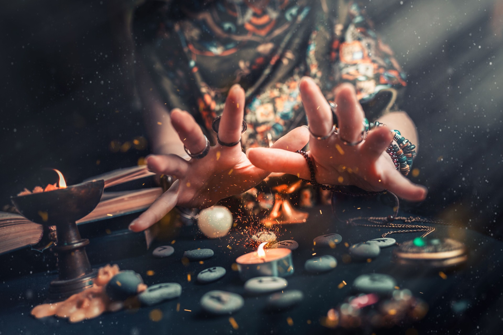 Astrology and esotericism. The witch at the candle and rune stones. Sparks of fire in the air. Dark background Astrology and esotericism. The witch at the candle and rune stones. Sparks of fire in the air. Dark background